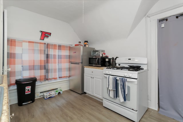 kitchen with appliances with stainless steel finishes, lofted ceiling, white cabinets, and light wood-type flooring