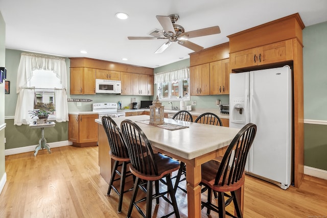 kitchen featuring white appliances, ceiling fan, a healthy amount of sunlight, and light wood-type flooring