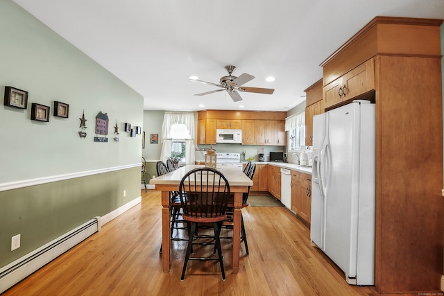 kitchen featuring white appliances, a baseboard radiator, a kitchen bar, light hardwood / wood-style floors, and ceiling fan