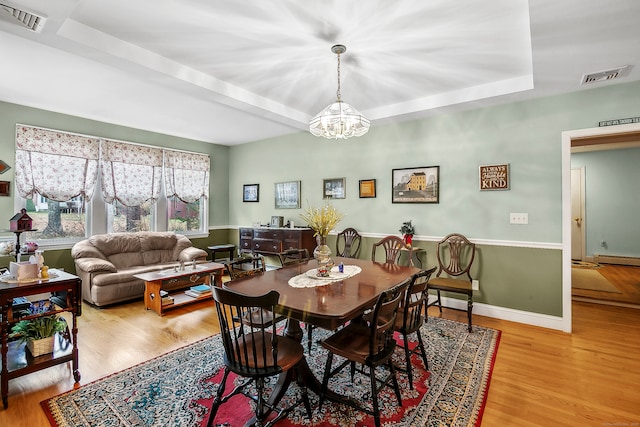 dining room featuring baseboard heating, light hardwood / wood-style flooring, and a chandelier