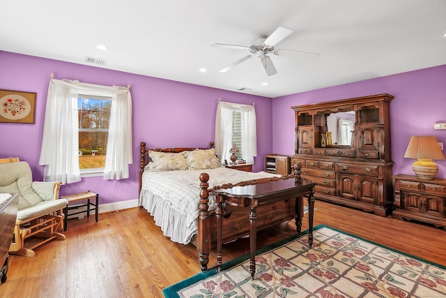 bedroom featuring light hardwood / wood-style flooring, ceiling fan, and multiple windows