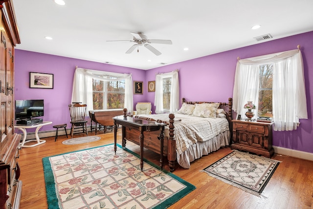 bedroom featuring ceiling fan, multiple windows, and hardwood / wood-style floors