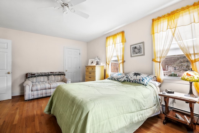 bedroom with ceiling fan, a baseboard radiator, and dark hardwood / wood-style flooring