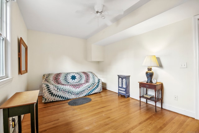 living area with wood-type flooring and ceiling fan