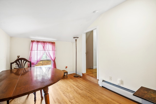 unfurnished dining area featuring hardwood / wood-style floors, a baseboard radiator, and vaulted ceiling