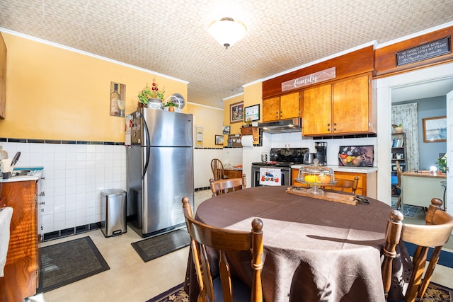 dining room featuring crown molding, tile walls, a wainscoted wall, and light floors