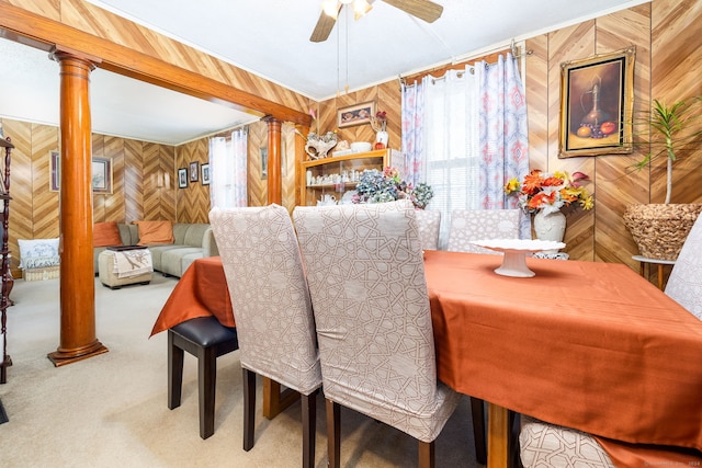dining space featuring wood walls, carpet, ornate columns, and ceiling fan