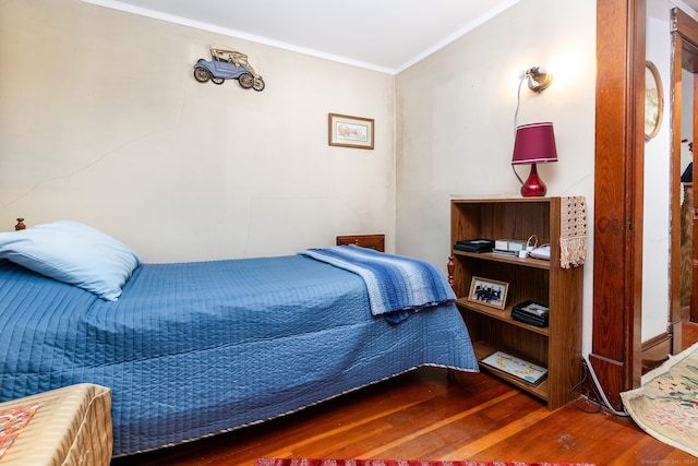 bedroom with wood finished floors and ornamental molding