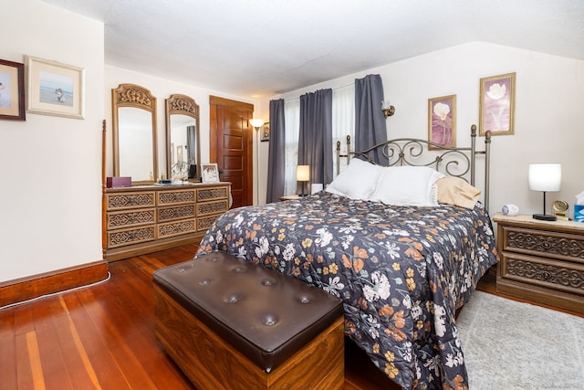bedroom with wood-type flooring, baseboards, and vaulted ceiling