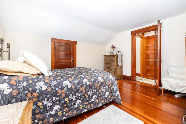 bedroom with wood finished floors and lofted ceiling