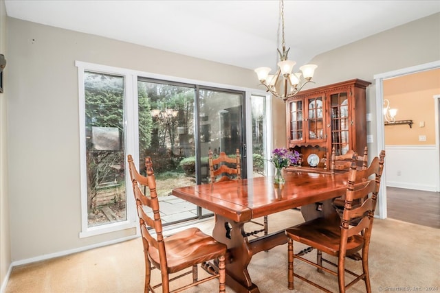 carpeted dining room with a healthy amount of sunlight and an inviting chandelier