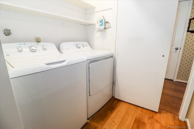 clothes washing area featuring light wood-type flooring and separate washer and dryer