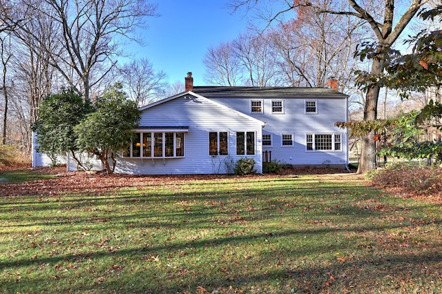 rear view of property with a lawn and a sunroom