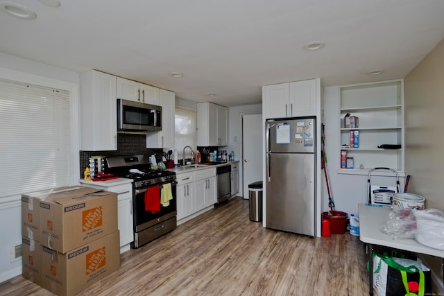 kitchen with sink, appliances with stainless steel finishes, light wood-type flooring, and white cabinetry