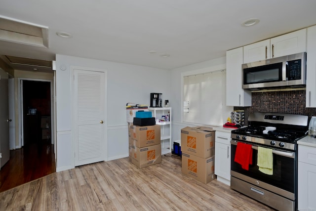 kitchen featuring appliances with stainless steel finishes, white cabinets, and light hardwood / wood-style floors