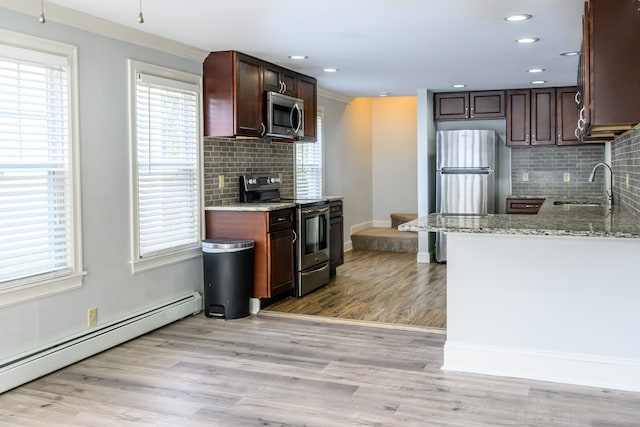 kitchen featuring a baseboard heating unit, backsplash, appliances with stainless steel finishes, light wood-type flooring, and sink