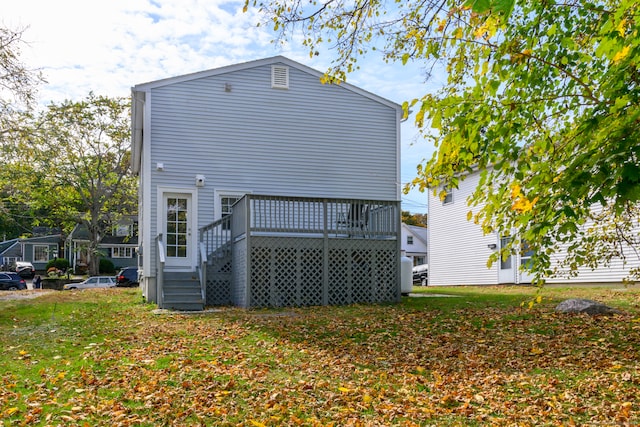 rear view of house with a wooden deck and a lawn