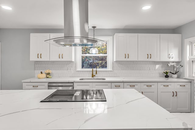 kitchen with white cabinetry, island exhaust hood, light stone countertops, and sink