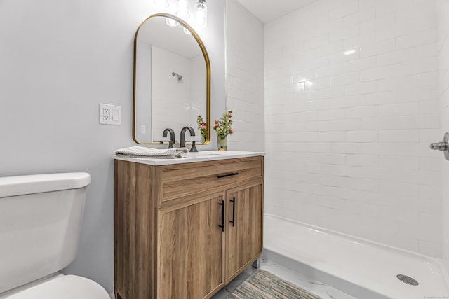 bathroom featuring toilet, vanity, and tiled shower