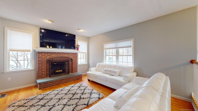 living room featuring a brick fireplace and hardwood / wood-style flooring