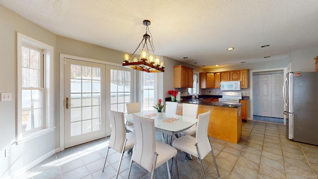 tiled dining space featuring a textured ceiling, sink, and an inviting chandelier