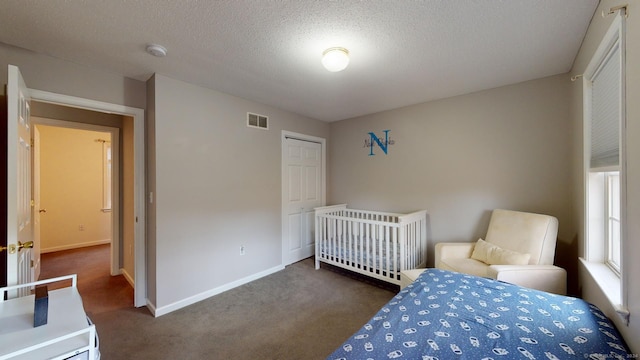 bedroom featuring a textured ceiling, a closet, and dark carpet