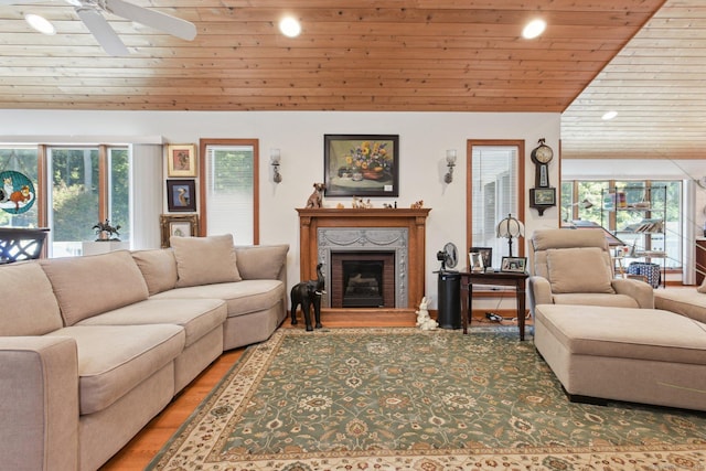 living room with wood ceiling, light wood-type flooring, a premium fireplace, vaulted ceiling, and a ceiling fan