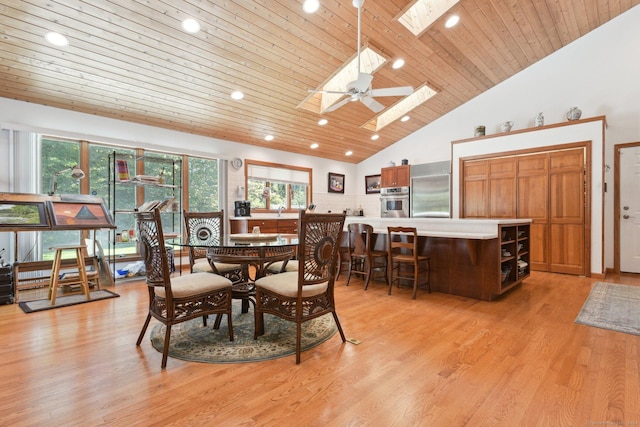 dining room with wood ceiling, high vaulted ceiling, a skylight, and light wood-style floors