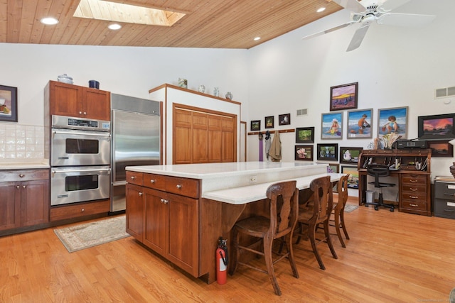 kitchen featuring light wood-style floors, appliances with stainless steel finishes, a skylight, light countertops, and wood ceiling