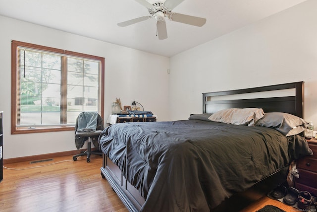 bedroom with visible vents, baseboards, wood finished floors, and a ceiling fan