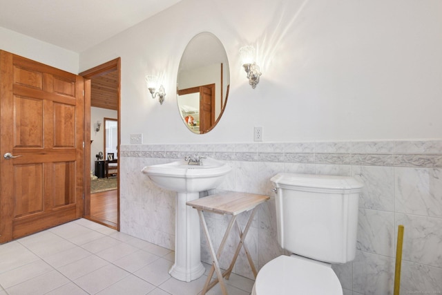 bathroom with tile patterned floors, a wainscoted wall, toilet, and tile walls