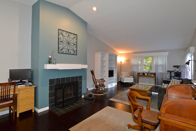 living room with dark hardwood / wood-style floors, a tiled fireplace, and vaulted ceiling