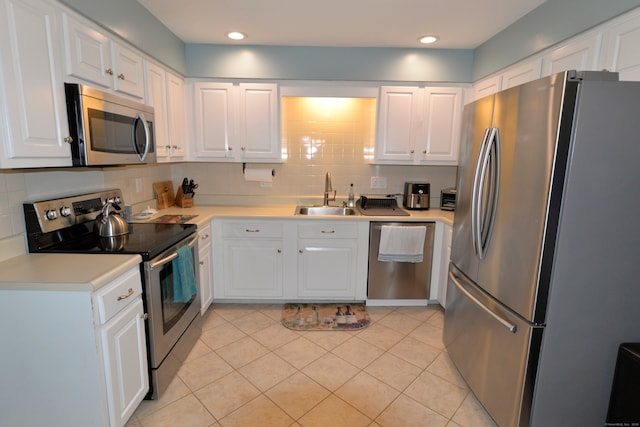 kitchen featuring light tile patterned floors, appliances with stainless steel finishes, backsplash, white cabinetry, and sink