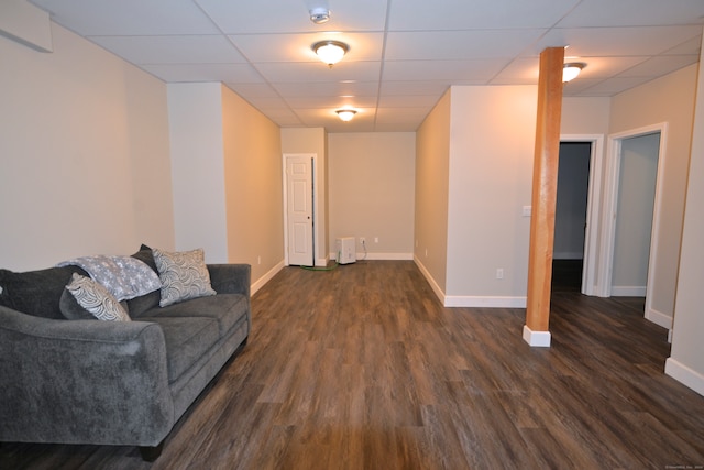 living room featuring dark wood-type flooring and a drop ceiling