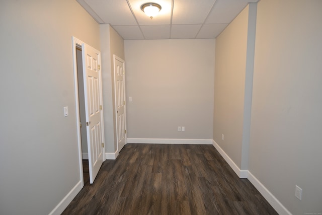 hallway with dark wood-type flooring and a paneled ceiling