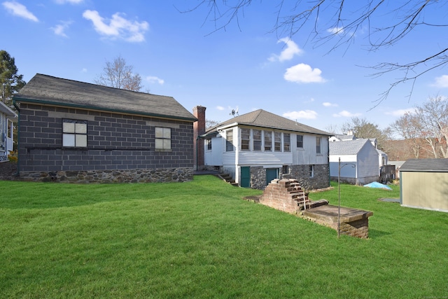 rear view of property with a storage unit and a yard