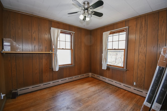 unfurnished room with wooden walls, wood-type flooring, and a wealth of natural light