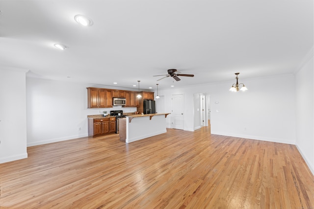 unfurnished living room with ceiling fan with notable chandelier, crown molding, and light hardwood / wood-style flooring