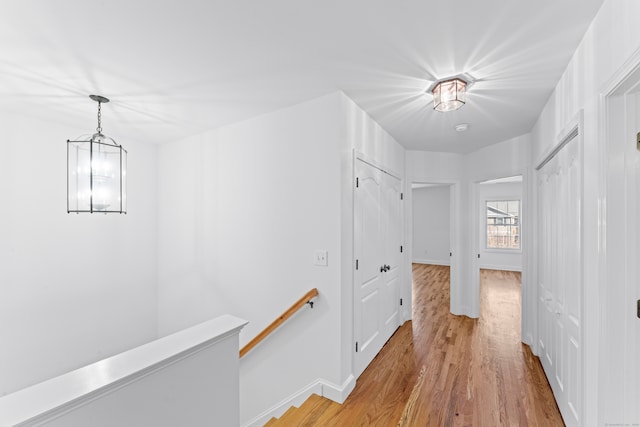 hall featuring light wood-type flooring and an inviting chandelier