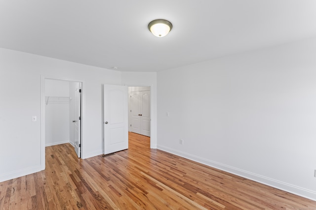 unfurnished bedroom with a closet, light wood-type flooring, and a walk in closet