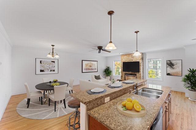 kitchen featuring sink, a kitchen bar, a center island with sink, and light hardwood / wood-style flooring