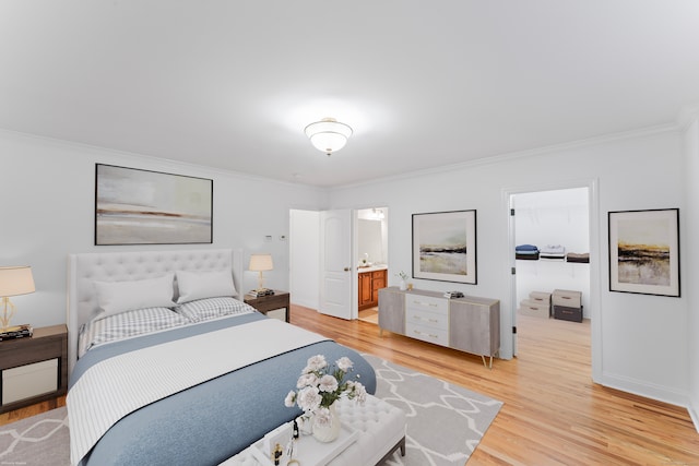 bedroom featuring ornamental molding, light hardwood / wood-style flooring, and connected bathroom