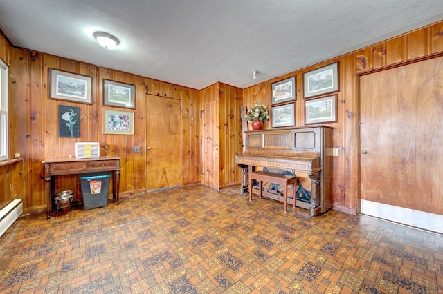 misc room with baseboard heating, wood walls, and a textured ceiling