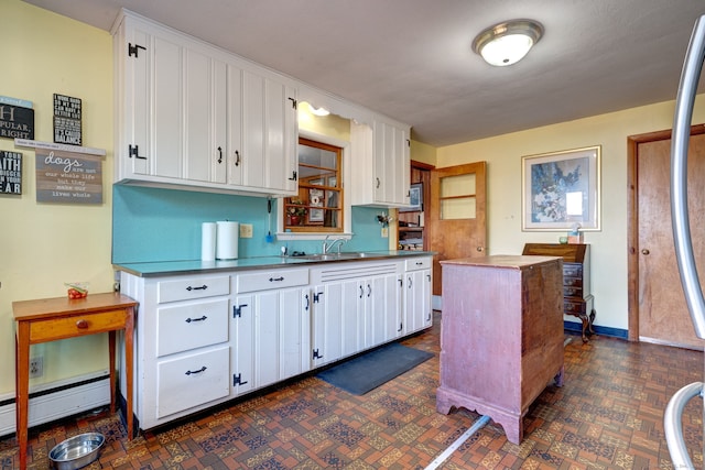 kitchen with white cabinets, a kitchen island, sink, and baseboard heating