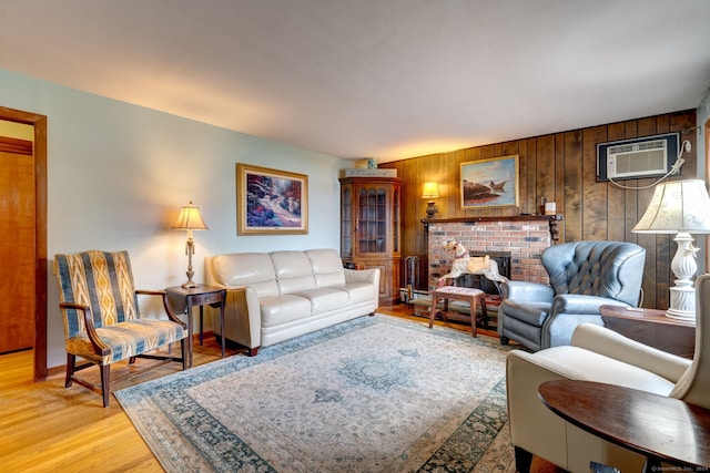 living room with wood walls, light hardwood / wood-style floors, a fireplace, and a wall mounted AC