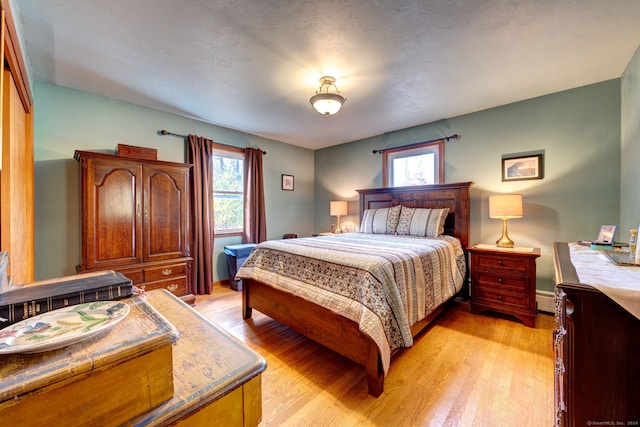 bedroom featuring light hardwood / wood-style floors and a textured ceiling