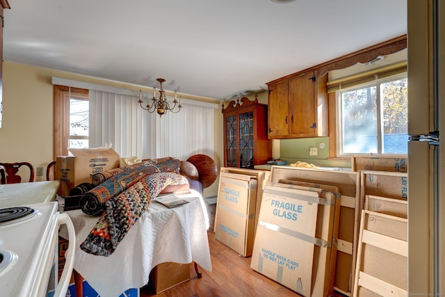 kitchen with a wealth of natural light, pendant lighting, light hardwood / wood-style floors, and a notable chandelier