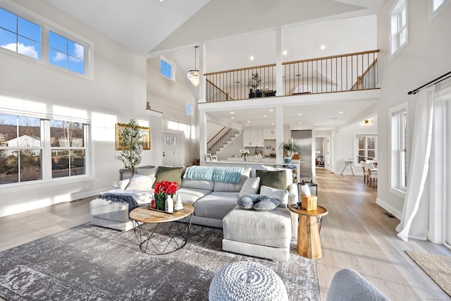 living room with a healthy amount of sunlight, high vaulted ceiling, and light hardwood / wood-style flooring