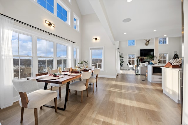 dining space with a towering ceiling, light hardwood / wood-style floors, and a wealth of natural light