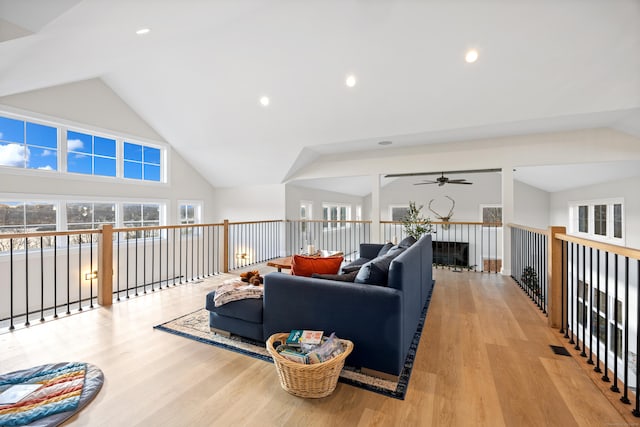 living room with ceiling fan, light wood-type flooring, and lofted ceiling